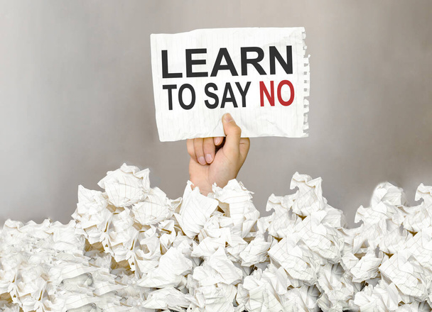 männliche Hand nehmen Sie ein Papier mit Text Learn to Say No mit einer Menge anderer Papier - Foto, Bild