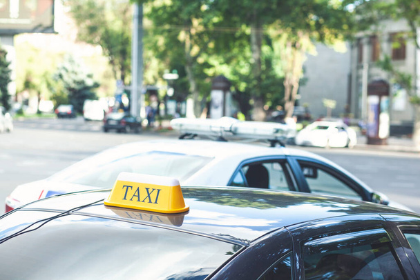 Zwarte taxi auto 's met gele standaard borden op de top geparkeerd of gestopt op drukke straat, taxi service. - Foto, afbeelding