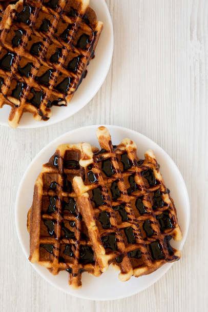 Beyaz ahşap bir masada beyaz bir tabakta nefis ev yapımı Belçika şekerli waffle 'ları. Dümdüz, tepeden, yukarıdan. Boşluğu kopyala. - Fotoğraf, Görsel