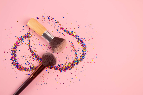 Set of professional cosmetics makeup brushes with explosion of shiny colorful sparkles on bright pink background with copyspace for your text. Creative make-up concept - Foto, Imagem