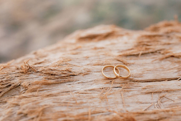 Anneaux de mariage en or sur un fond flou de texture rugueuse en bois. - Photo, image