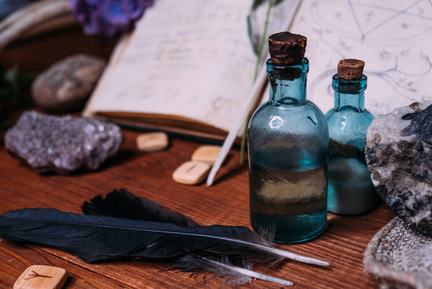 Magic potion bottle. Witchcraft halloween concept with potions, herbs and occult equipment. Magical still life with copy space on a dark background. - Photo, Image