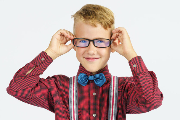 A portrait of a schoolboy adjusting his glasses. Education concept. - Фото, изображение