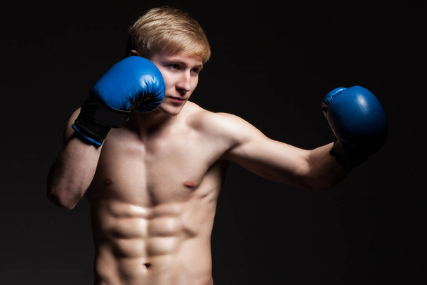 Młody przystojny bokser w niebieskich rękawiczkach na ciemnym tle - Zdjęcie, obraz