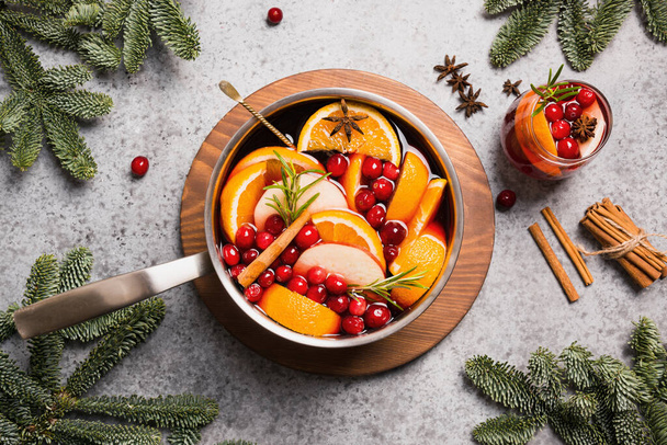 Mulled wine with cinnamon, cranberry, orange in ladle and glass on grey table. - Foto, imagen