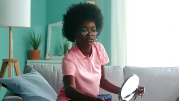 Молода чорна жінка - студент дивиться в дзеркало за столом - Кадри, відео