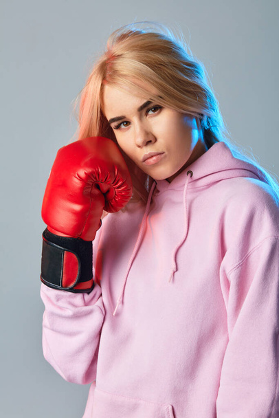 Sporty sexy woman wearing pink hoodie and red boxing gloves on white background - Foto, Imagem
