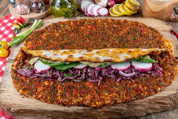 Deliciosa pizza turca lahmacun closeup em uma mesa de madeira. com salada de limão e ayran. Lahmacun turco entre verduras verdes em um fundo branco. Conceito de restaurante Lahmacun. - Foto, Imagem