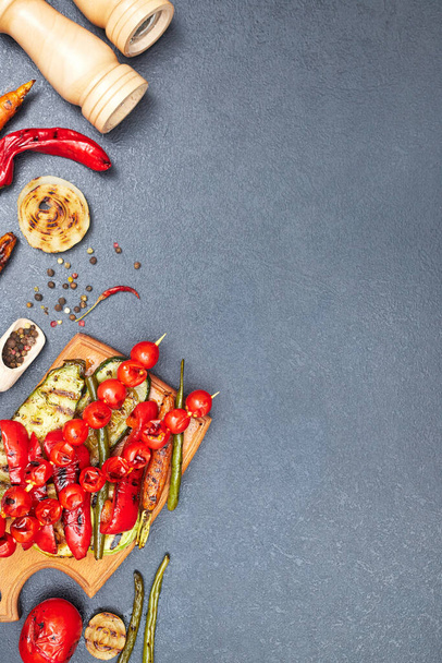 grilled vegetables on a wooden board on a black table, copyspace, top view - Foto, Imagem