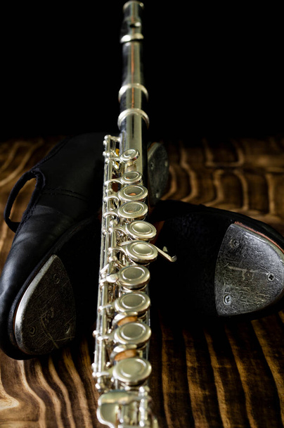 dettagli della scarpa da tip tap e del flauto a croce argento, fondo nero, breve profondità di campo. - Foto, immagini