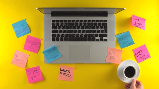 Werkplaats met post het papier op het bureau, laptop op gele achtergrond, koffiepauze - Video