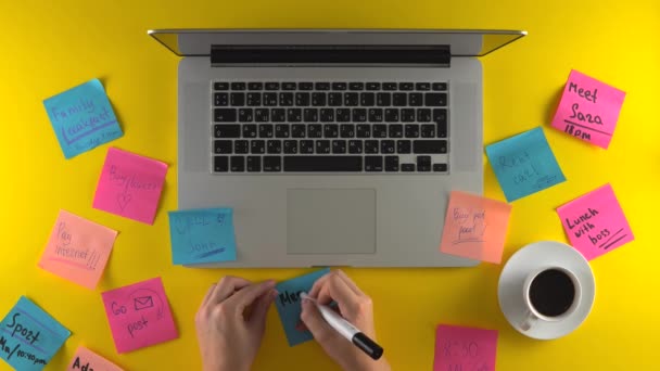 Írás a post it papírok, hogy emlékeztető jegyzetek, laptop az asztalon sárga háttér - Felvétel, videó