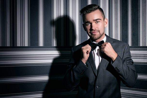 Portrait of a handsome man in a suit and a tie who is posing over a striped background - Photo, Image