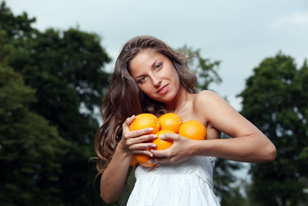 Beautiful woman with fresh oranges in her hands - Foto, Imagen