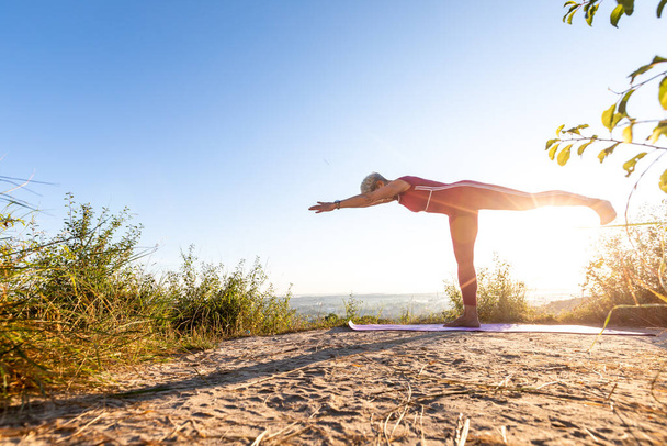 yoga master practicing yoga on the grass at sunrise - Фото, зображення
