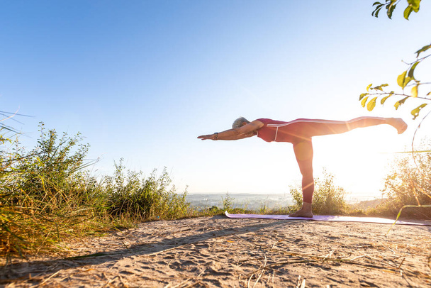 kobieta praktykująca jogę na trawie o wschodzie słońca - Zdjęcie, obraz