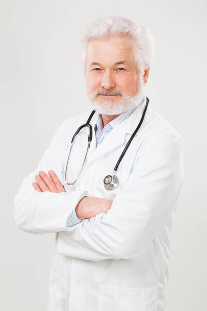 Handsome elderly doctor in uniform isolated over light background - Photo, Image