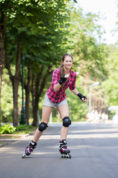 Beautiful girl rides her rollerblades in park - Photo, Image