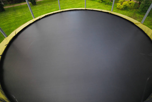 trampoline met grote ronde mat op groen gazon - Foto, afbeelding
