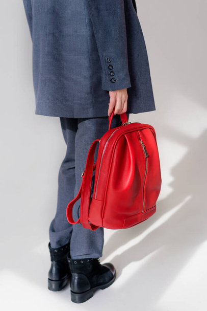 Elinde kırmızı deri bir sırt çantası tutan bir kız. - Fotoğraf, Görsel