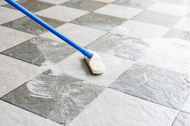 Очистите пол плиткой с помощью длинноручной щетки. - Фото, изображение