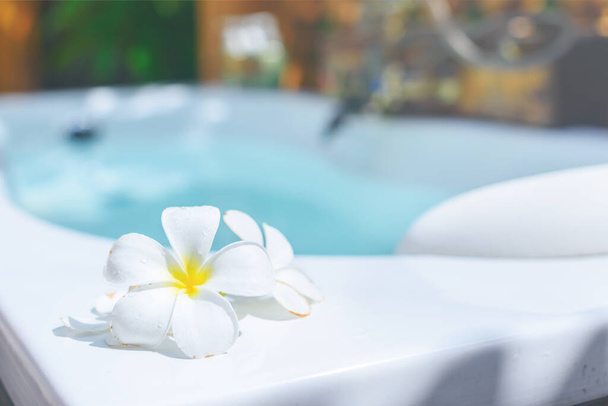 Wet white plumeria petals on the bathtub of tropical pool villa. Wellness and spa concept. Escape. Background. Copy space. Holiday. - Fotó, kép