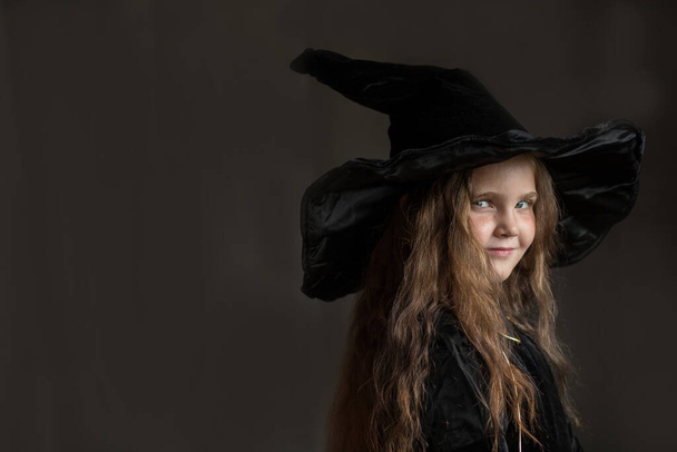 Litlles Mädchen im Halloween-Hexenkostüm auf grauem Hintergrund  - Foto, Bild