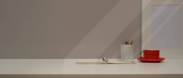 Close up άποψη του χώρου εργασίας με γραφική ύλη, φλιτζάνι καφέ, mock up πλαίσιο και αντίγραφο χώρο σε λευκό τραπέζι  - Φωτογραφία, εικόνα