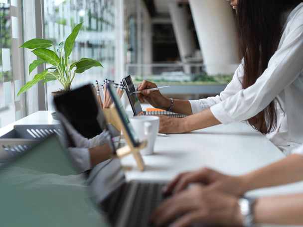 Vista lateral das trabalhadoras de escritório trabalhando juntas e digitando no teclado na sala de escritório moderna - Foto, Imagem