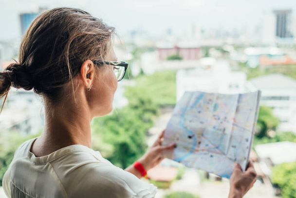 Achterzijde van reiziger meisje op zoek naar de juiste richting op de kaart, reizen langs Azië. Vrijheid en actief leefstijlconcept - Foto, afbeelding
