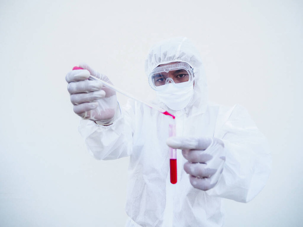 Médecin ou scientifique asiatique en uniforme de la suite PPE. Combinaison d'équipement de protection individuelle laissant tomber un sang dans une éprouvette sanguine. coronavirus ou COVID-19 concept isolé fond blanc - Photo, image