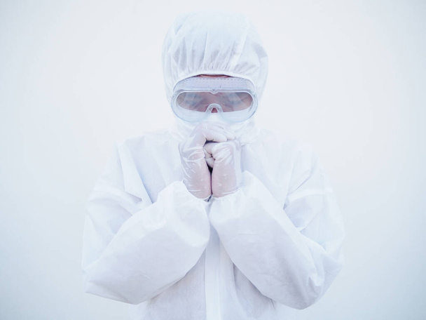 Szoros ázsiai férfi orvos vagy tudós PPE lakosztály egyenruha stressz és imádkozni kitörése során a koronavírus vagy COVID-19 izolált fehér háttér.  - Fotó, kép