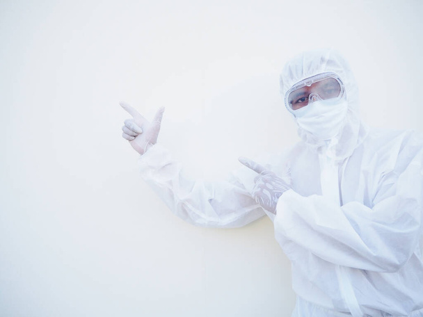 Médico ou cientista asiático em uniforme de suíte PPE mostrando apontando dois dedos de distância no espaço de cópia enquanto está de pé e olhando para frente. coronavírus ou COVID-19 conceito isolado fundo branco - Foto, Imagem