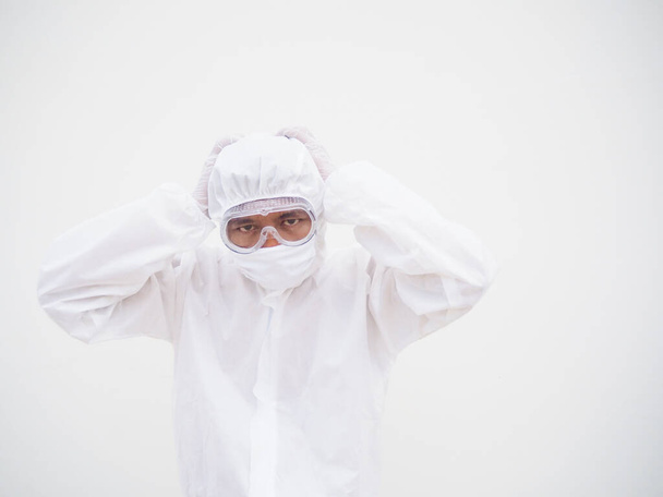 Aasialainen mies lääkäri tai tiedemies PPE-sviitissä univormussa tavalla, joka asettaa kätensä hänen päänsä päälle tunne strees ja päänsärky. koronavirus tai COVID-19-konsepti eristetty valkoinen tausta - Valokuva, kuva