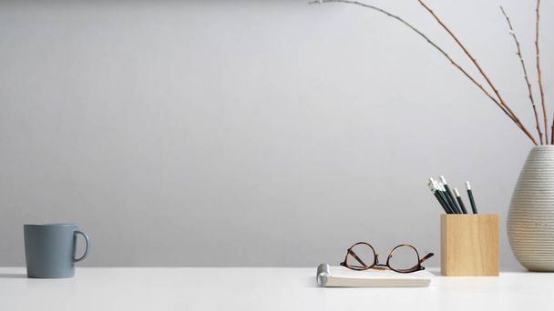 Vue rapprochée de la table d'étude avec papeterie, lunettes, cahier, tasse, décoration et espace de copie dans le bureau à domicile  - Photo, image