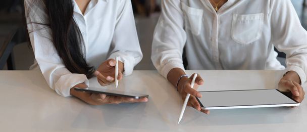 Lähikuva naisten kädet käyttäen digitaalisia tabletteja valkoisella pöydällä yhteistyössä työtilassa  - Valokuva, kuva