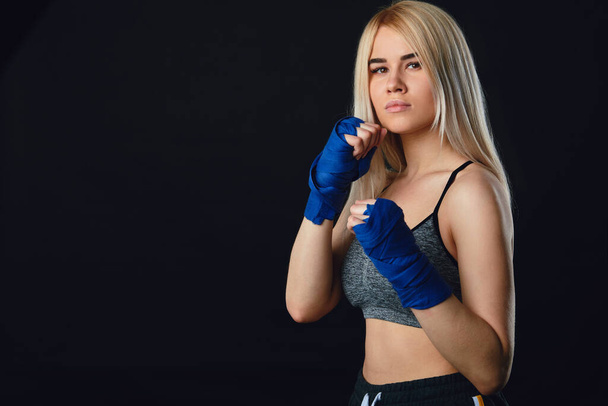Attractive blonde sportswoman in kickboxing bandages in defensive stance - Fotografie, Obrázek