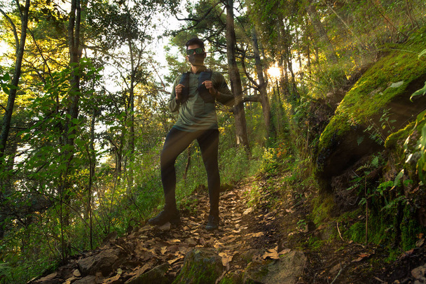 Runner φορώντας μάσκα τρέχει μέσα από το φθινόπωρο δάσος το πρωί κατά την ανατολή του ηλίου - Φωτογραφία, εικόνα