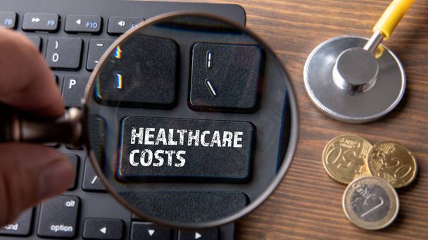 Охорона здоров'я COSTS. Комп'ютерна клавіатура на дерев'яному столі
 - Фото, зображення