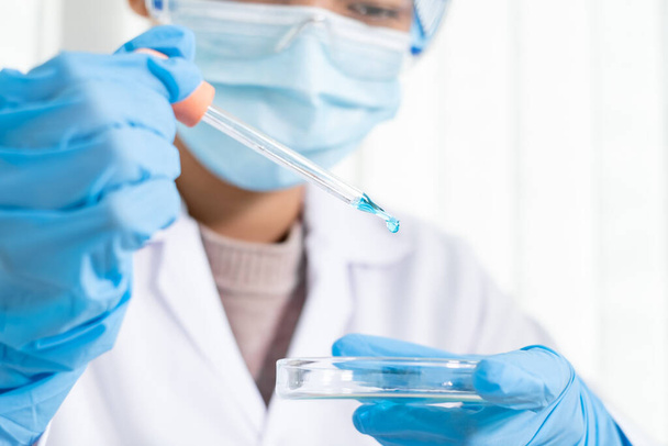 Medycy wypuścili próbkę pipety do szklanego naczynia do analizy wirusa w laboratorium chemicznym. Koncepcje badań naukowych. - Zdjęcie, obraz