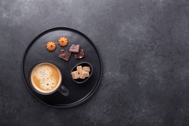 Cup of coffee, biscuits, chocolate and brown sugar on ceramic plate. Stone table. Copy space for your text - Image - Foto, afbeelding