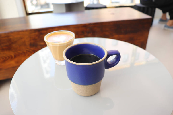 Порожня чашка і чашка кави на білому столі
 - Фото, зображення