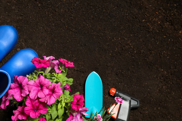 Flat lay composition with gardening tools and flowers on soil, space for text - Photo, Image
