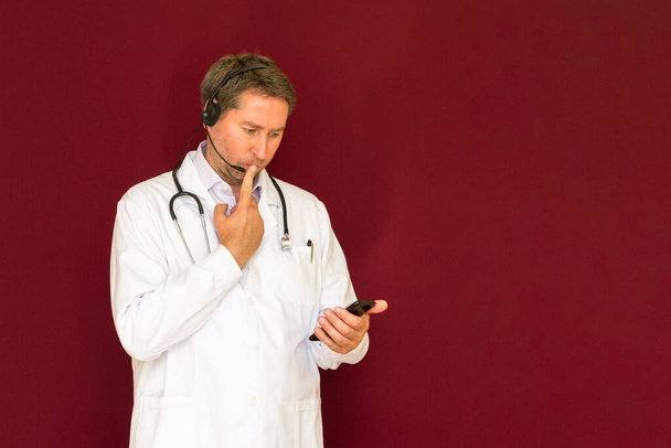 Młody kaukaski lekarz ze stetoskopem rozmawia z pacjentem online czerwone studio tle - Zdjęcie, obraz