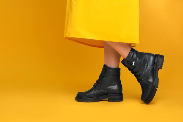 Woman wearing stylish boots on yellow background, closeup. Space for text - Foto, Imagen