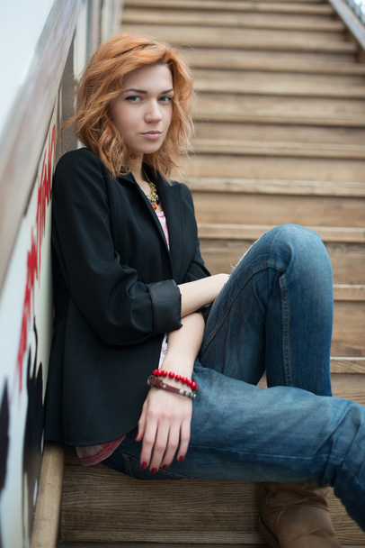 Beautiful girl sitting on wooden stairs - Foto, afbeelding