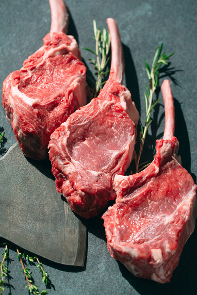 Raw steak with a meat cleaver on a dark stone background. - Zdjęcie, obraz