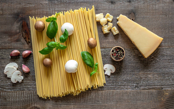 Zestaw produktów do pysznego włoskiego makaronu spaghetti z grzybami. Widok z góry, stary drewniany stół - Zdjęcie, obraz