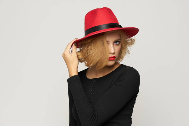 Modna kobieta w czerwonym kapeluszu czarny kapelusz bluzka czerwone usta przycięte widok światło tło emocje - Zdjęcie, obraz