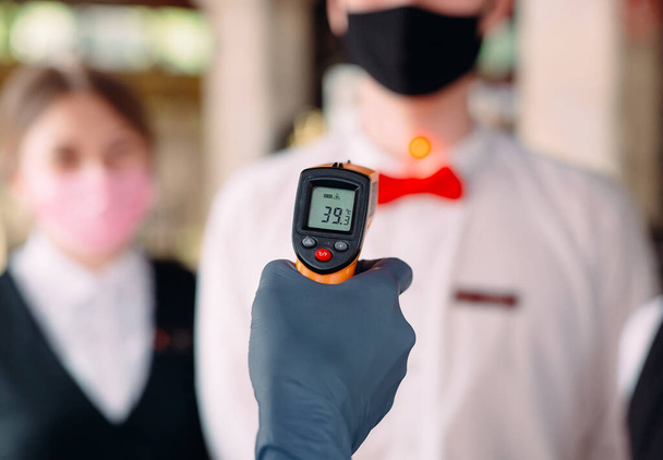 The Manager of a restaurant or hotel checks the body temperature of the staff with a thermal imaging device. - Foto, Bild